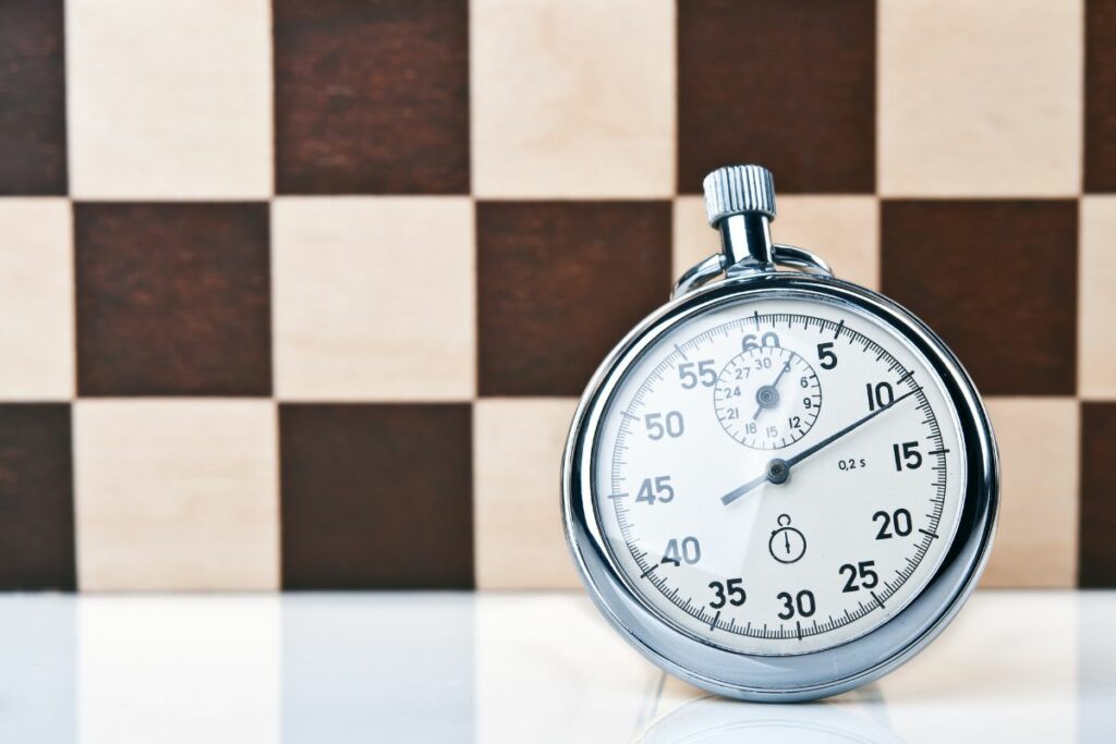 a photo of a stopwatch and a chessboard to show how do chess games last so long